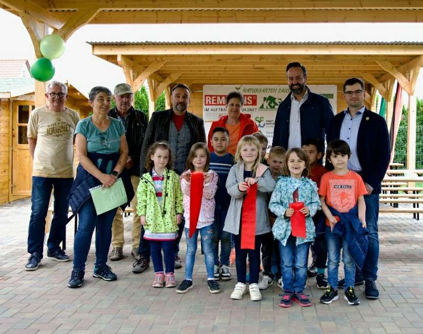 Eine Gruppe von Kindern und Erwachsenen posiert fröhlich im Naturgarten.