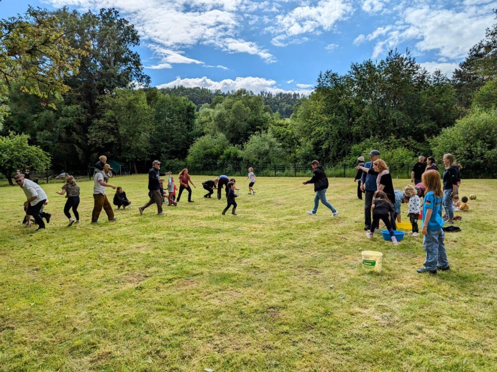 Kinder und Erwachsenen spielen auf einer Wiese.