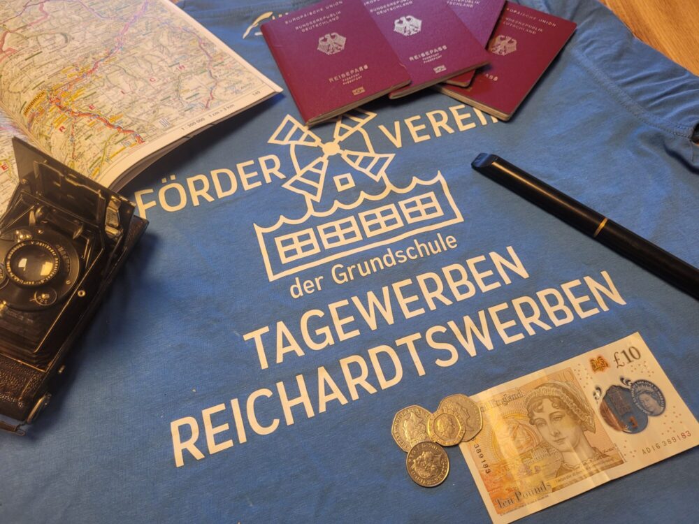 Stilleben mit dem Logo des Fördervereins, Reisepässen und ausländischem Bargeld.