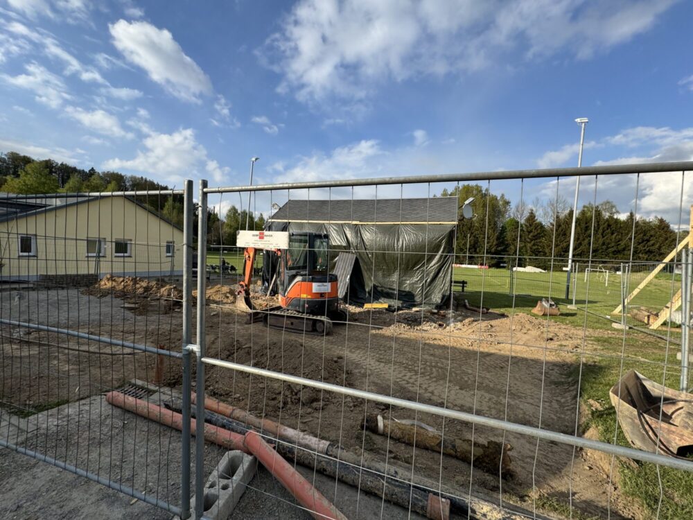 Blick durch einen Bauzaun auf die Baustelle des Sportvereins