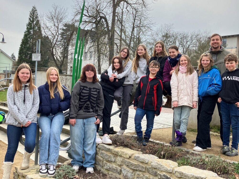 Eine Gruppe Jugendlicher posiert auf einer Treppe im Freien.