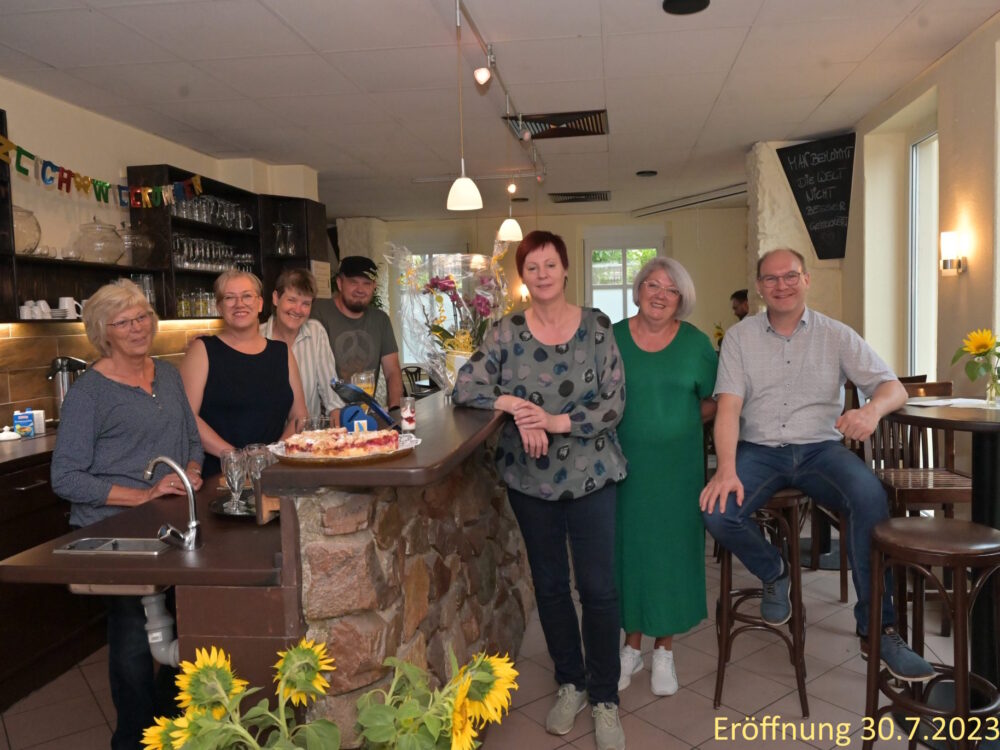 Eine Gruppe von Menschen posiert fröhlich an einem Restaurant-Tresen.