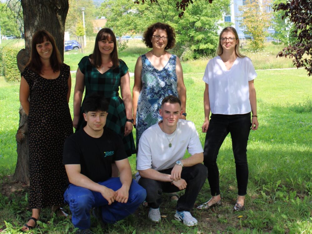 Gruppenfoto von Jugendlichen und Erwachsenen auf einer Wiese.